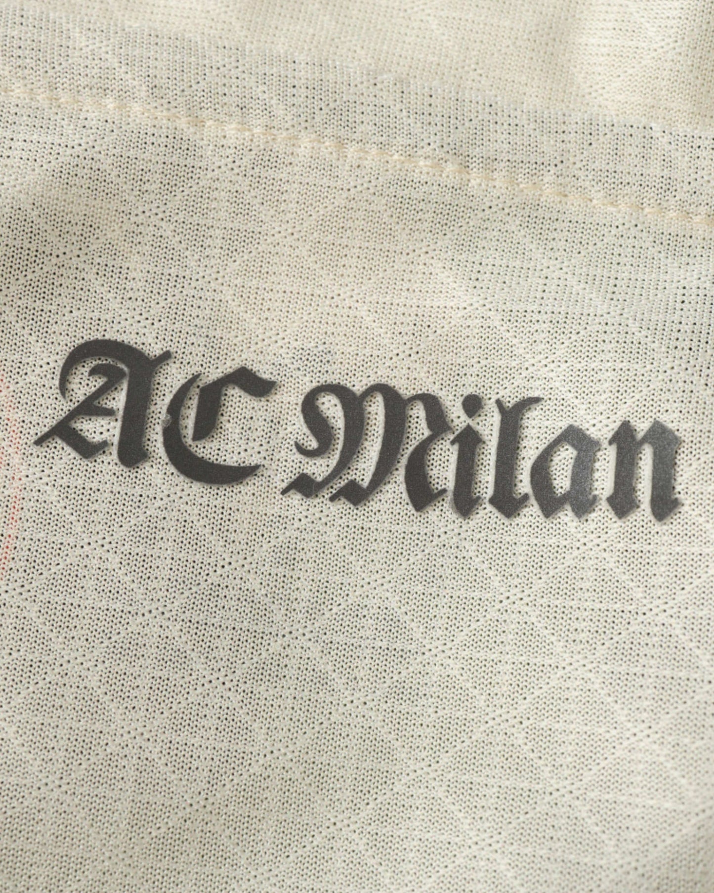 AC Milan fourth football jersey 2024/25 close-up of ACM crest on cream textured fabric