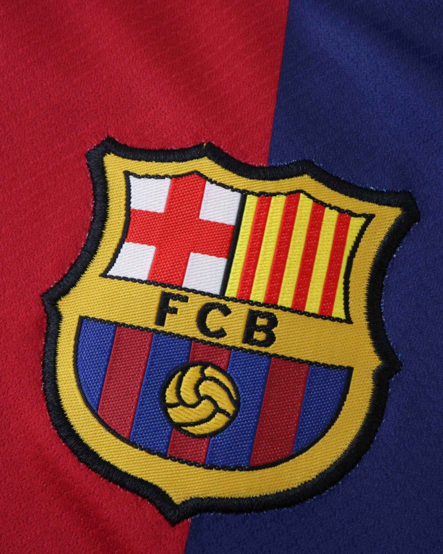 Barcelona x Cactus Jack kids football jersey close-up of FC Barcelona crest on red and blue