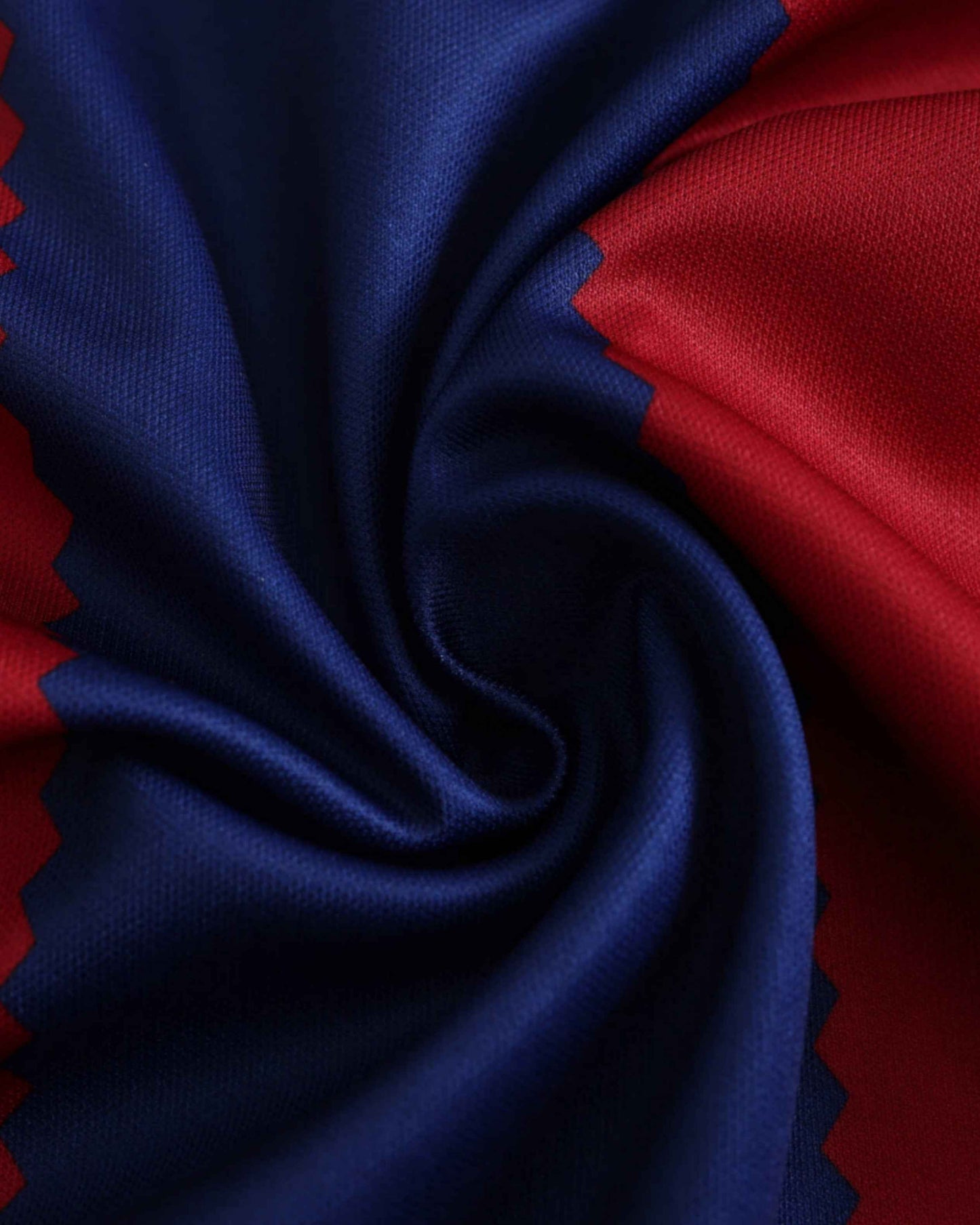 A close-up of a blue and red soccer jersey with a swirled fabric texture.