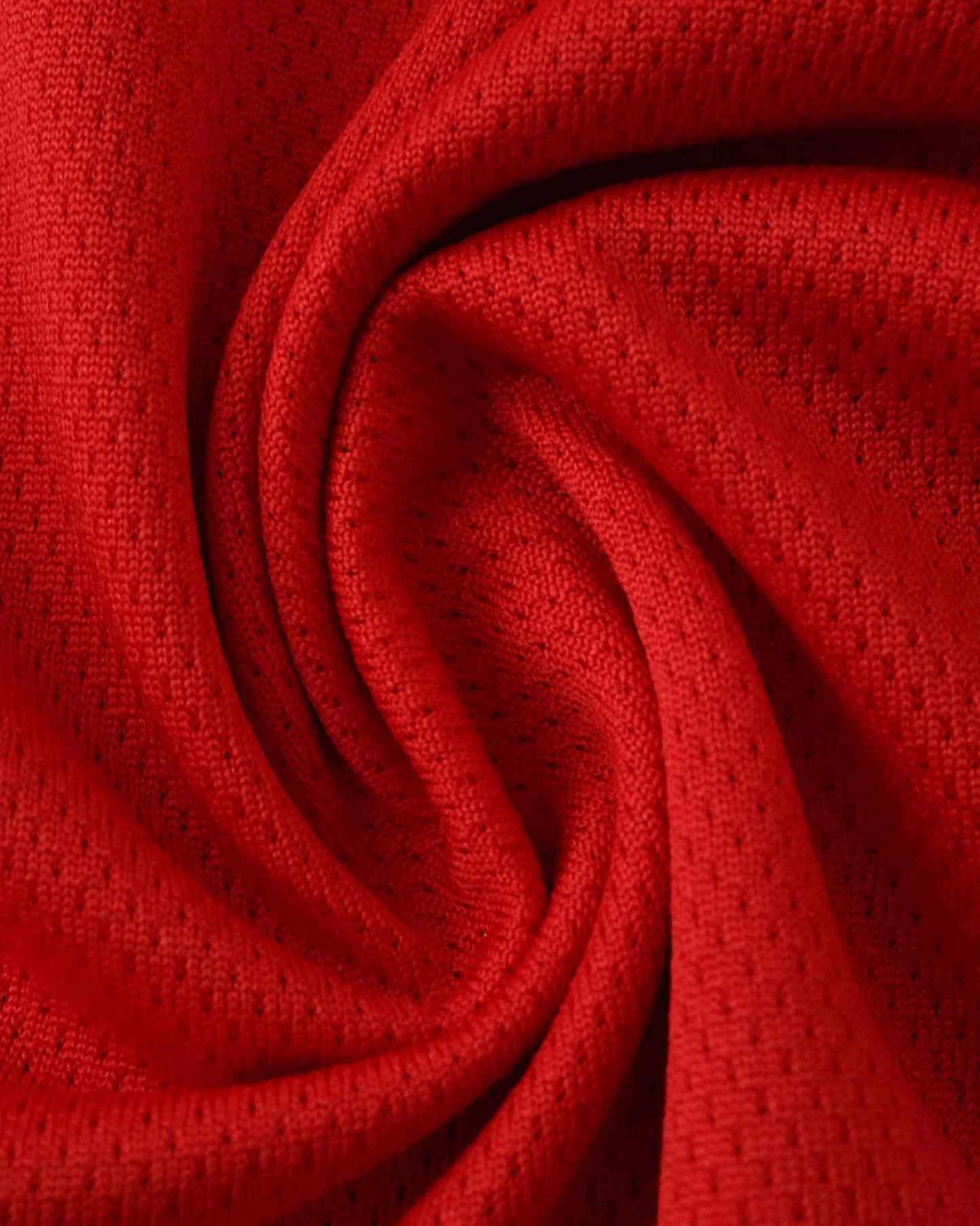 Red textured fabric with small perforations, folded into a swirl.