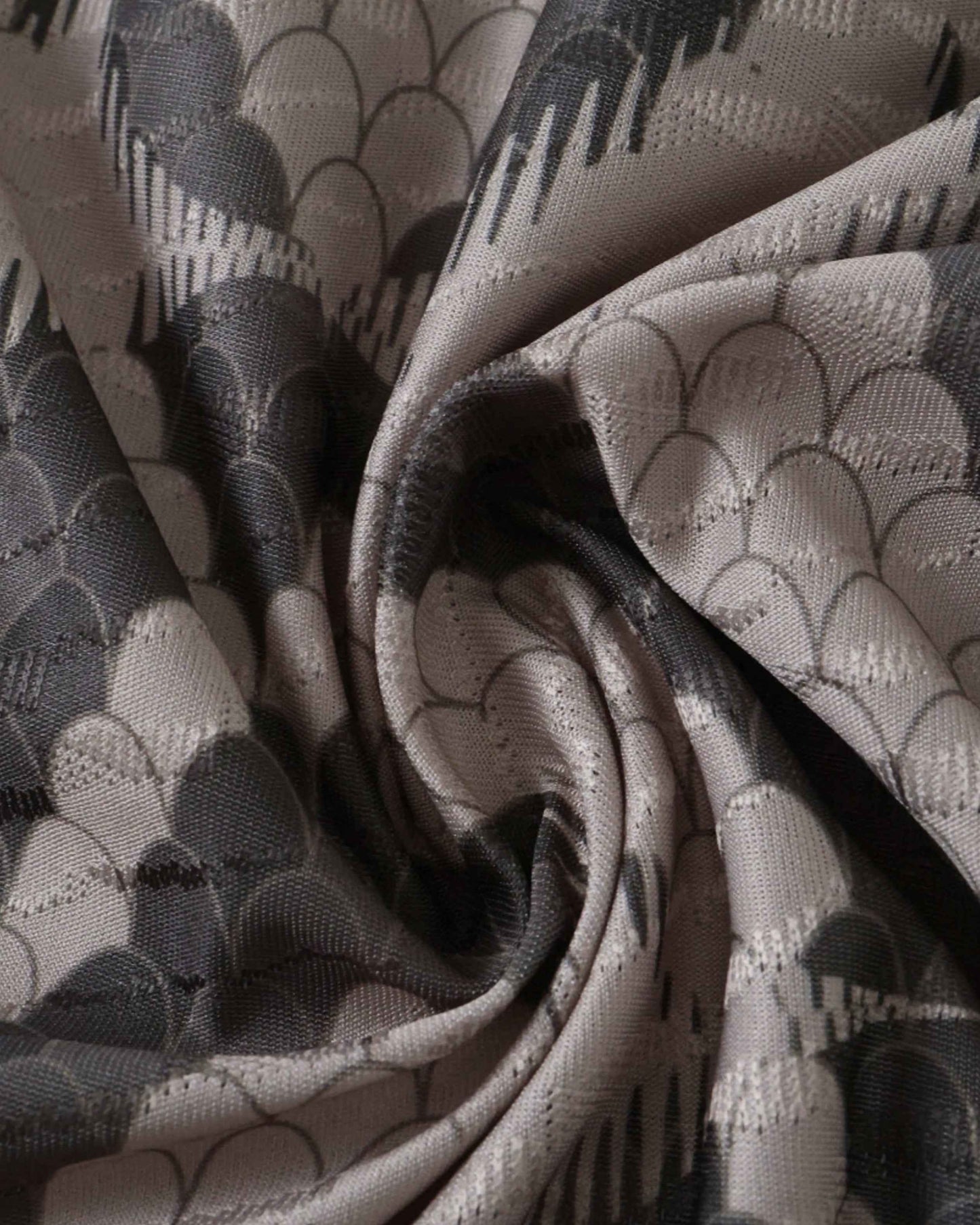 A close-up of grey fabric with a scale-like pattern.