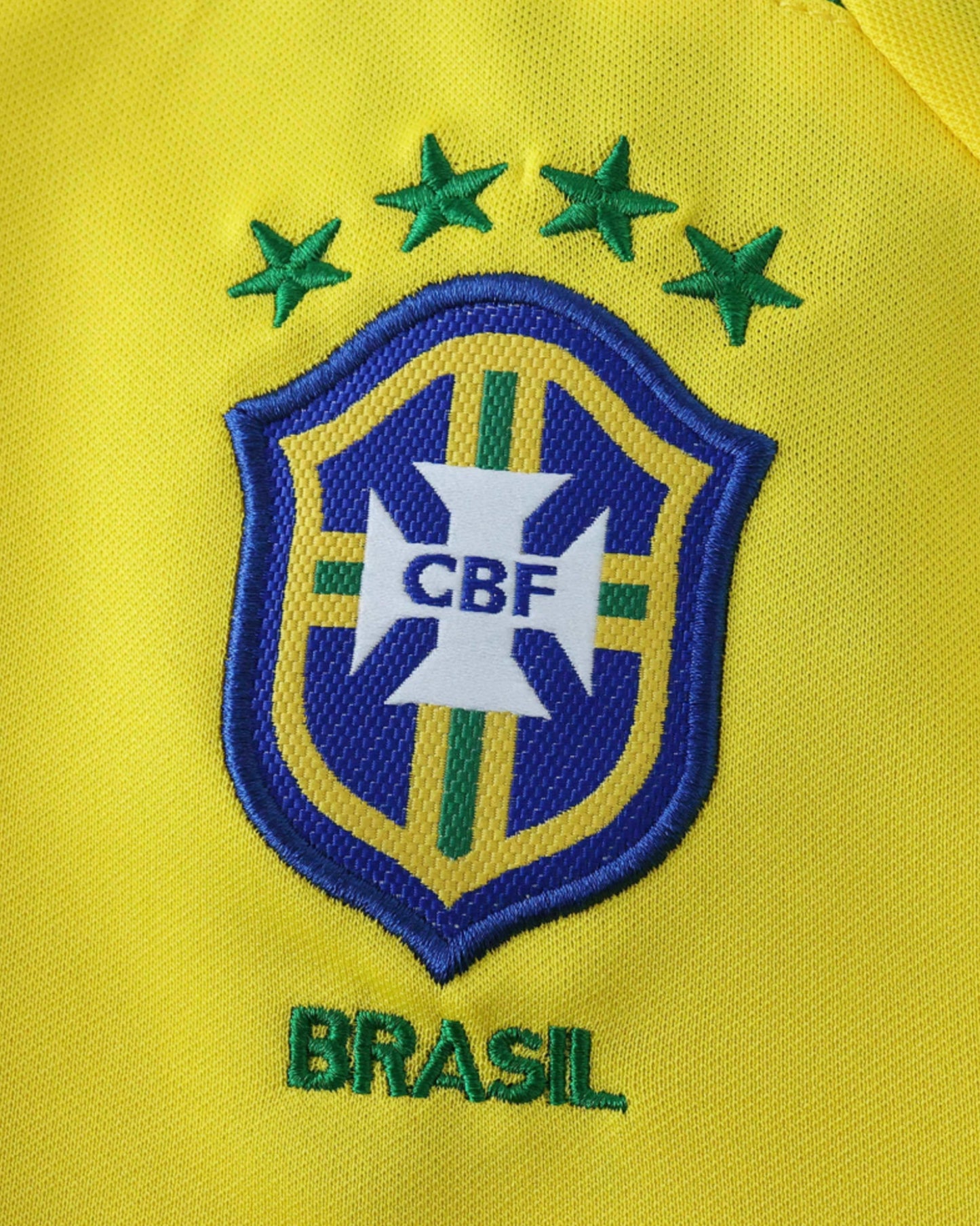 Close-up of gold CBF crest and BRASIL text on the yellow 2003/04 retro home kids football jersey