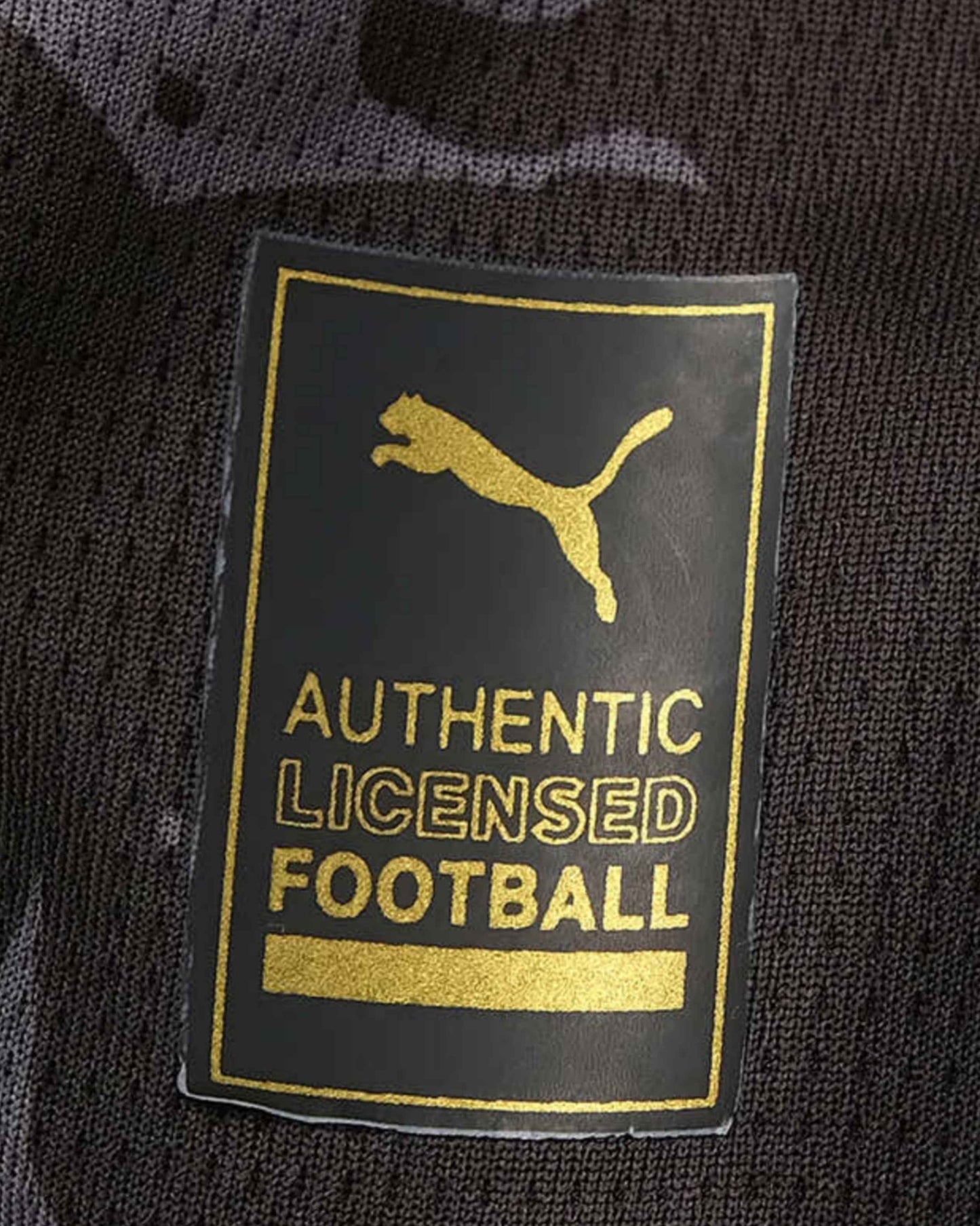 A black football jersey with a gold Puma logo and "Authentic Licensed Football" text.