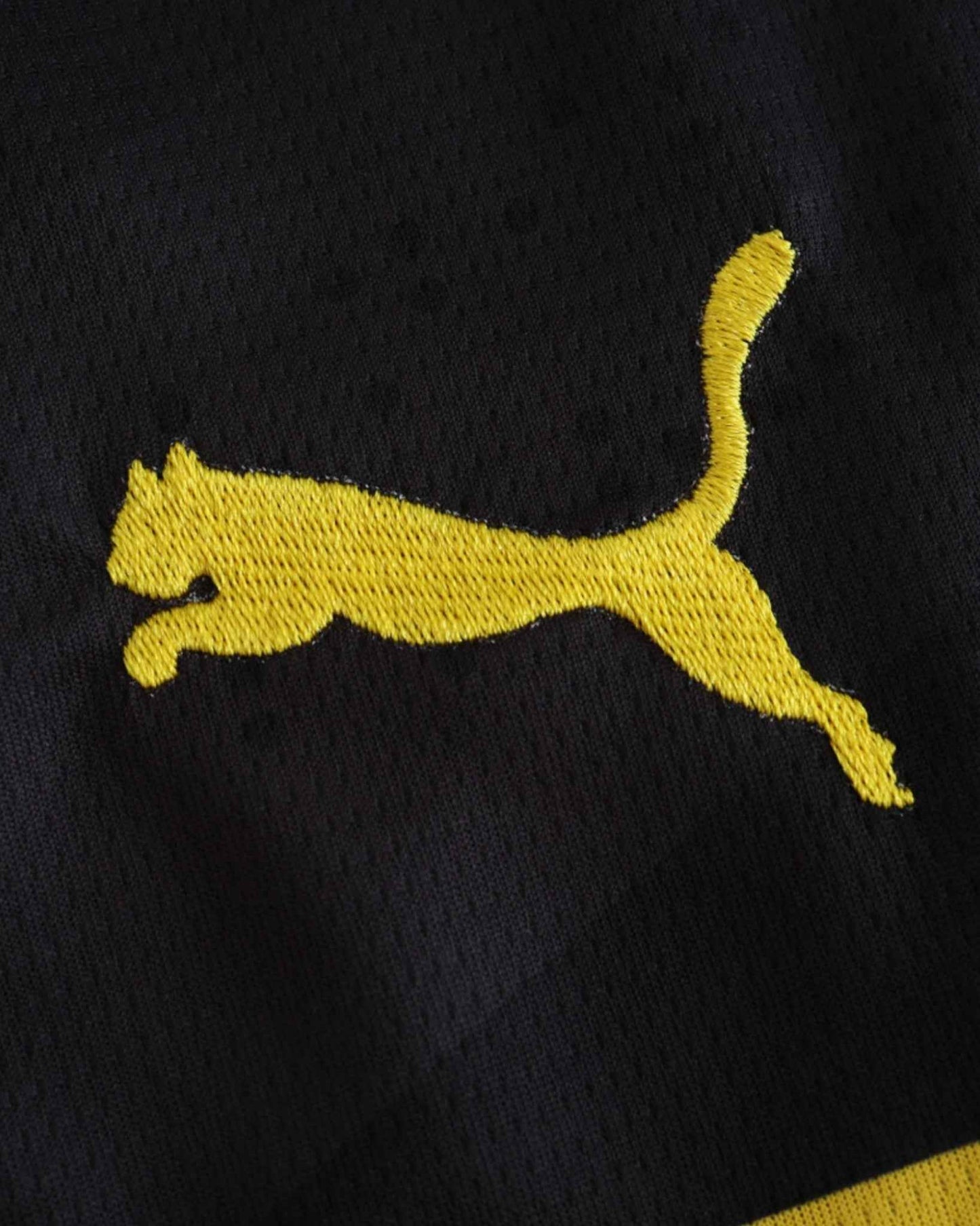 A yellow Puma logo is embroidered on a black fabric.