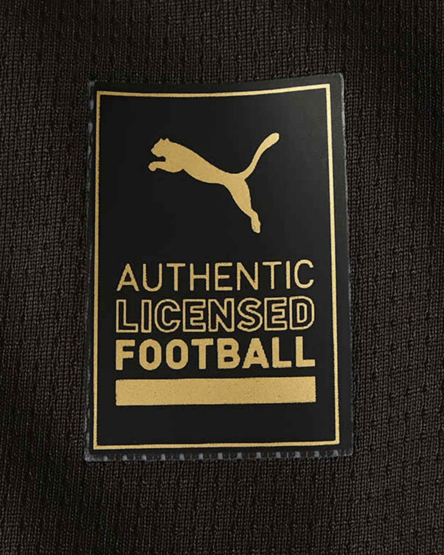 A black Puma tag with a gold puma logo and text that reads "AUTHENTIC LICENSED FOOTBALL".
