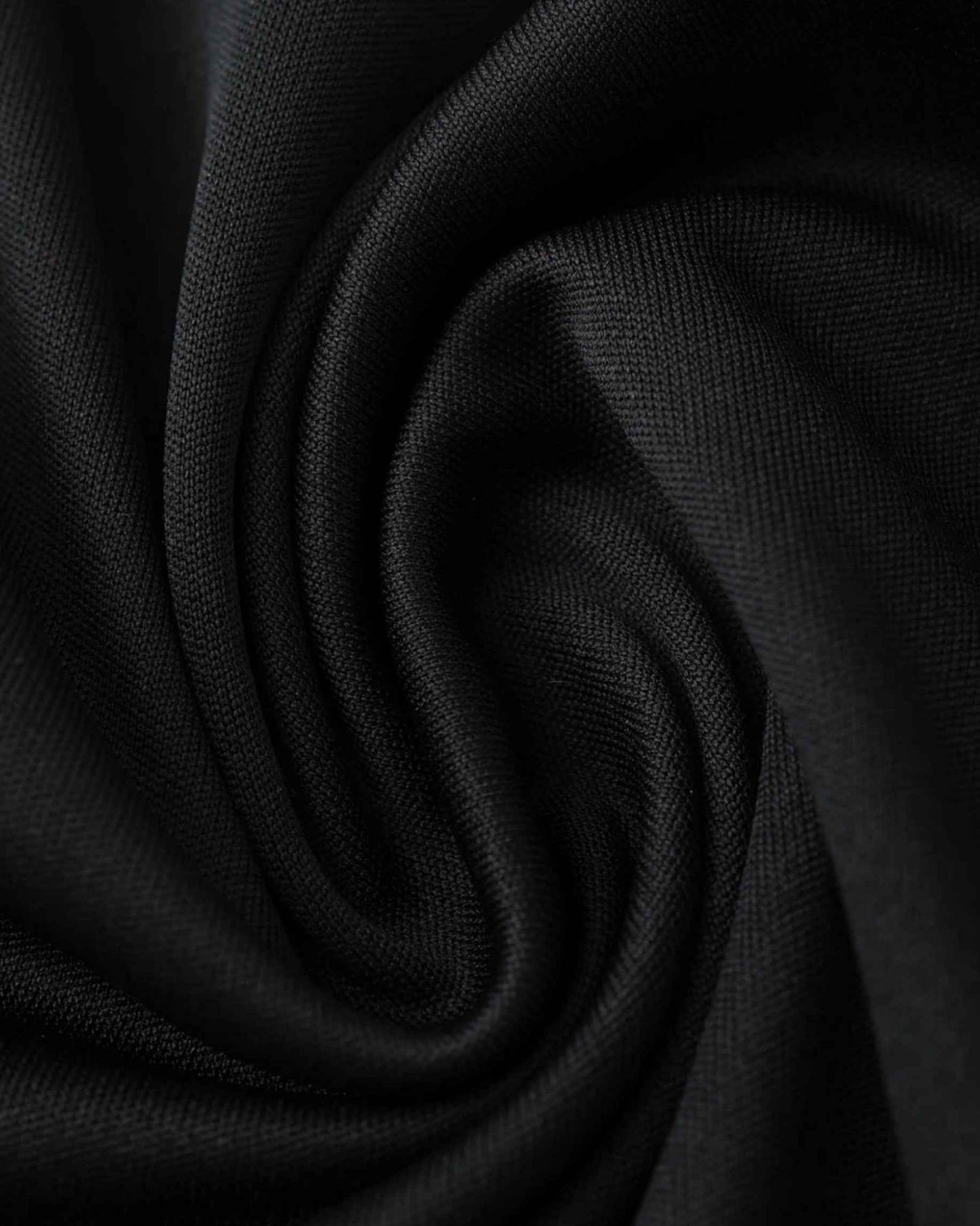 Black fabric with a textured weave, draped in soft folds.