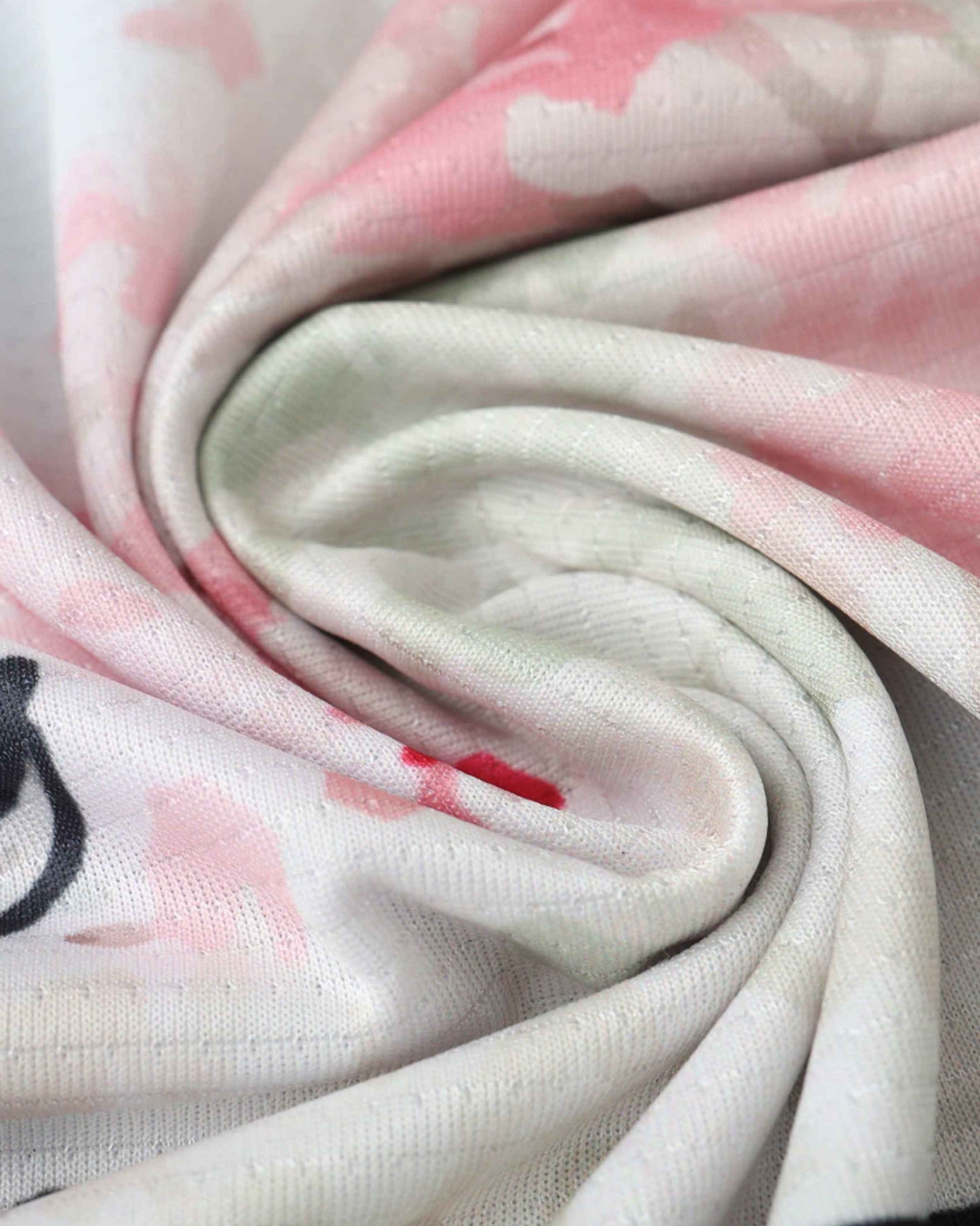 Close-up of a fabric with a watercolor floral print in pink and green.