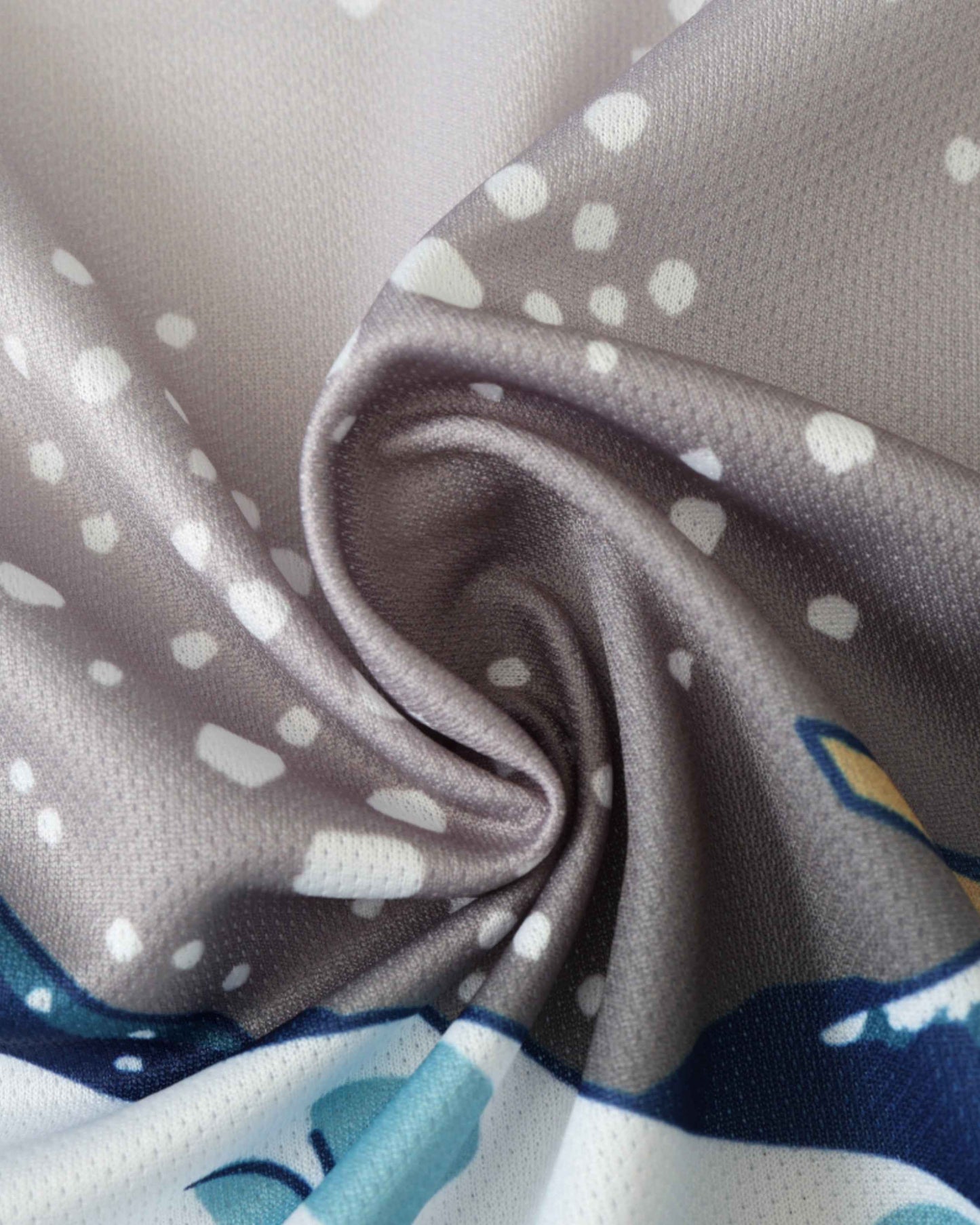 Close-up of a grey fabric with white polka dots and blue and yellow accents.