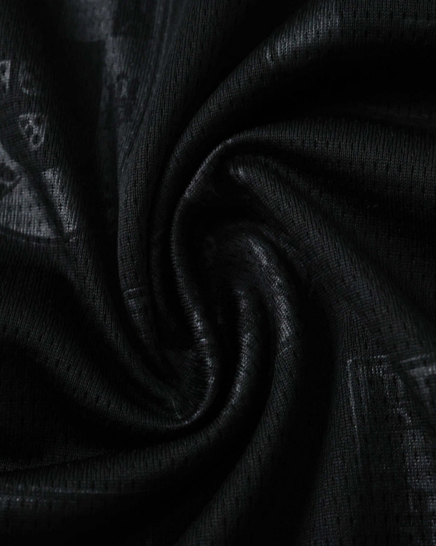Close-up of the tonal shield textured fabric on the black Portugal x Puma Eusebio premium football jersey