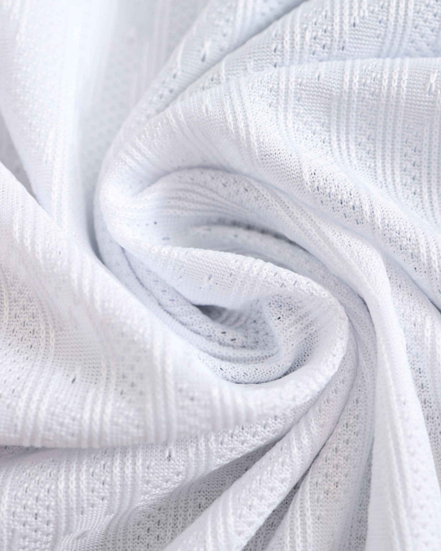 White knit fabric with a textured pattern and small holes.