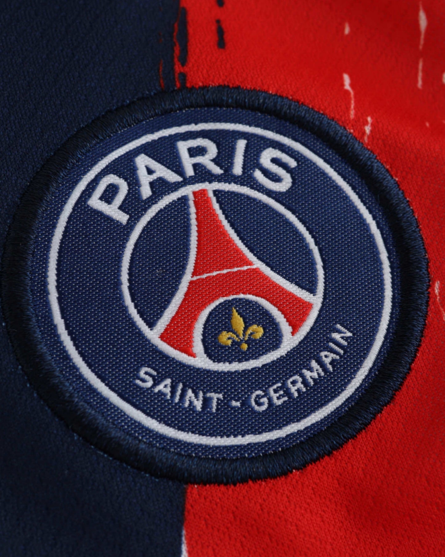 PSG away kids football jersey 2024/25 close-up of Paris Saint-Germain crest with red and blue brushstroke