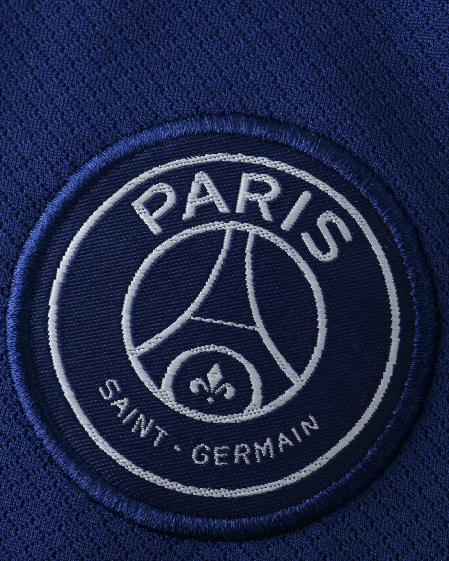 PSG fourth kids football jersey 2024/25 detail of Paris Saint-Germain crest on navy blue shirt