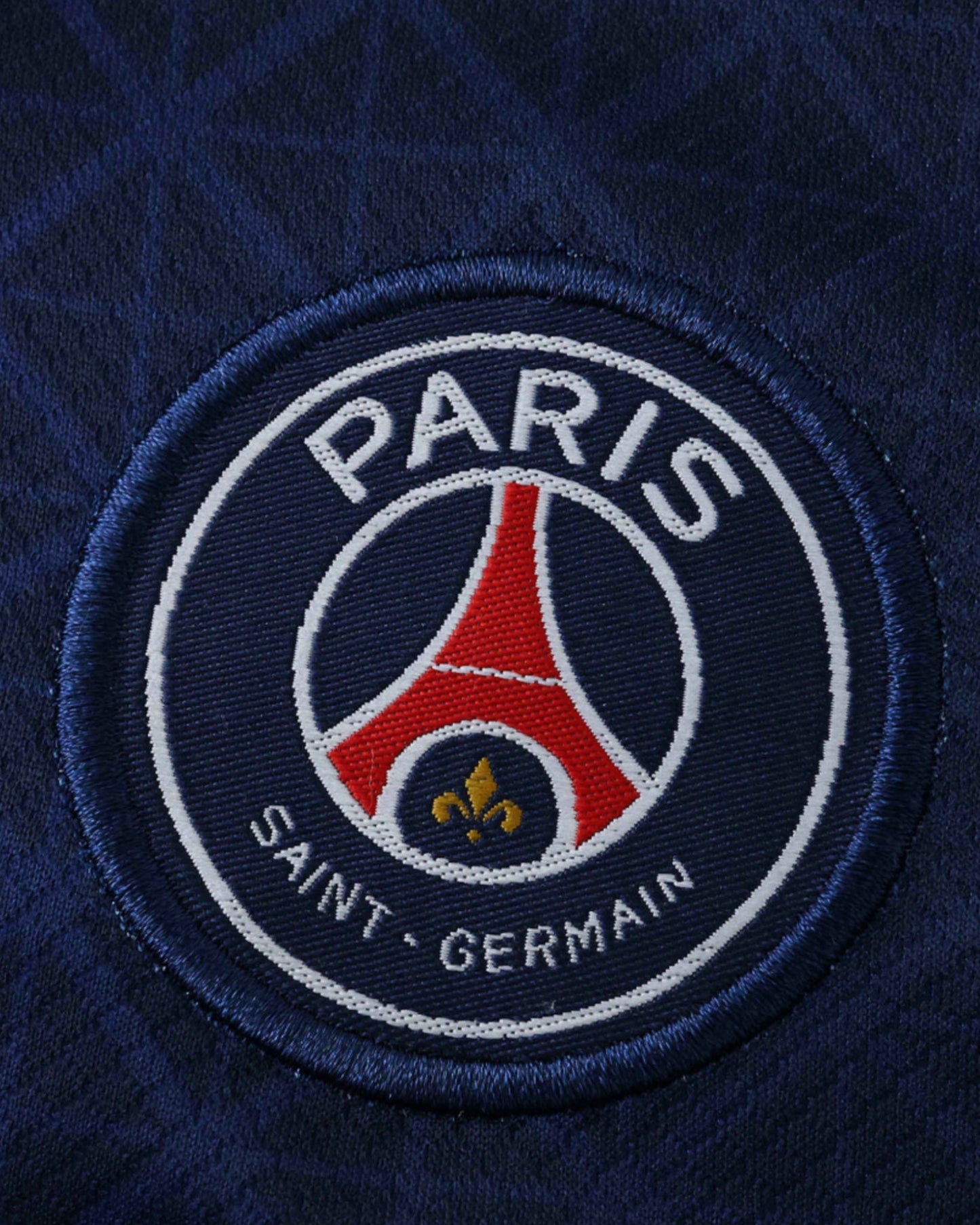 PSG home kids football jersey 2025/26 close-up of Paris Saint-Germain crest on navy shirt
