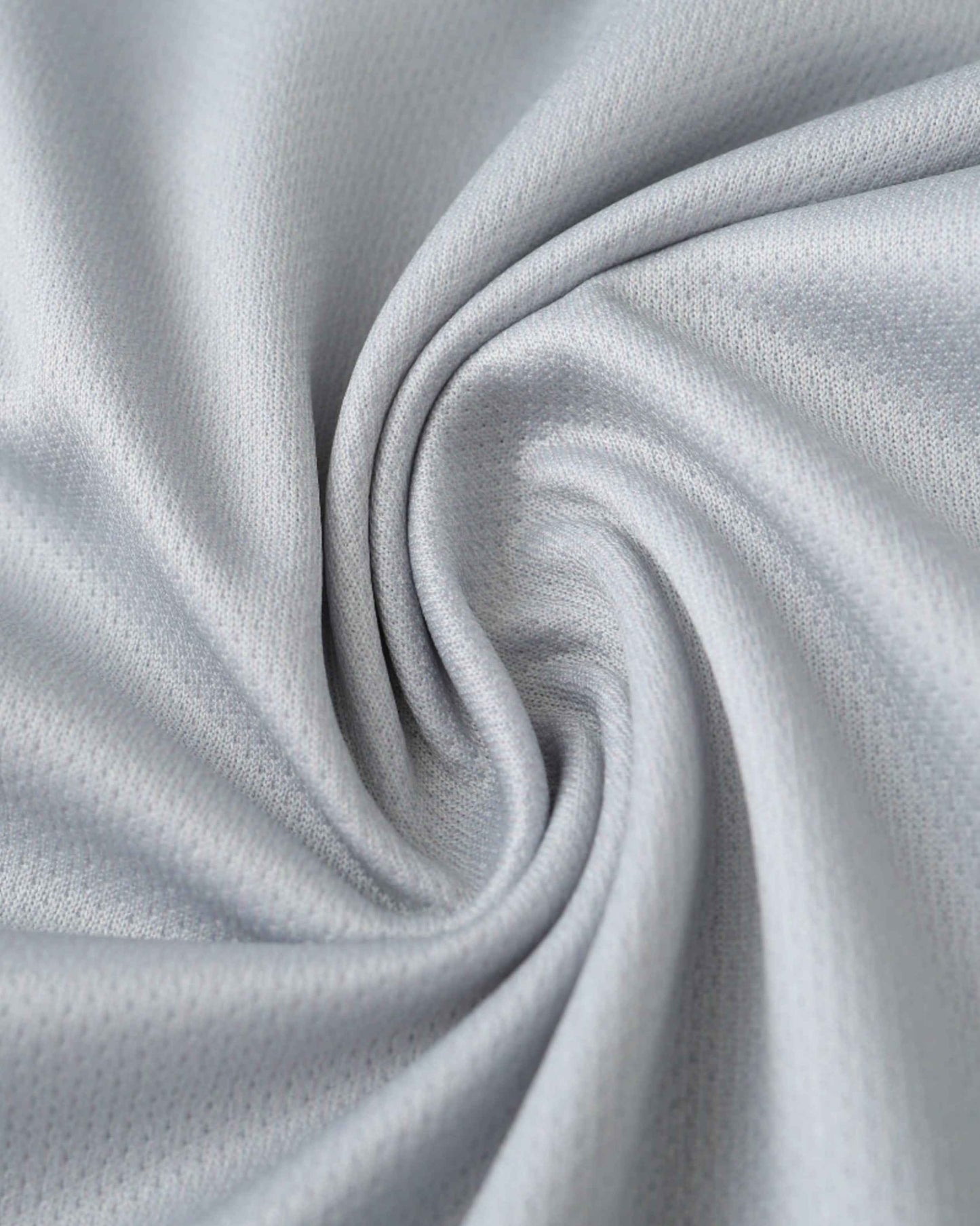 A close-up of a light grey, textured fabric with soft folds.