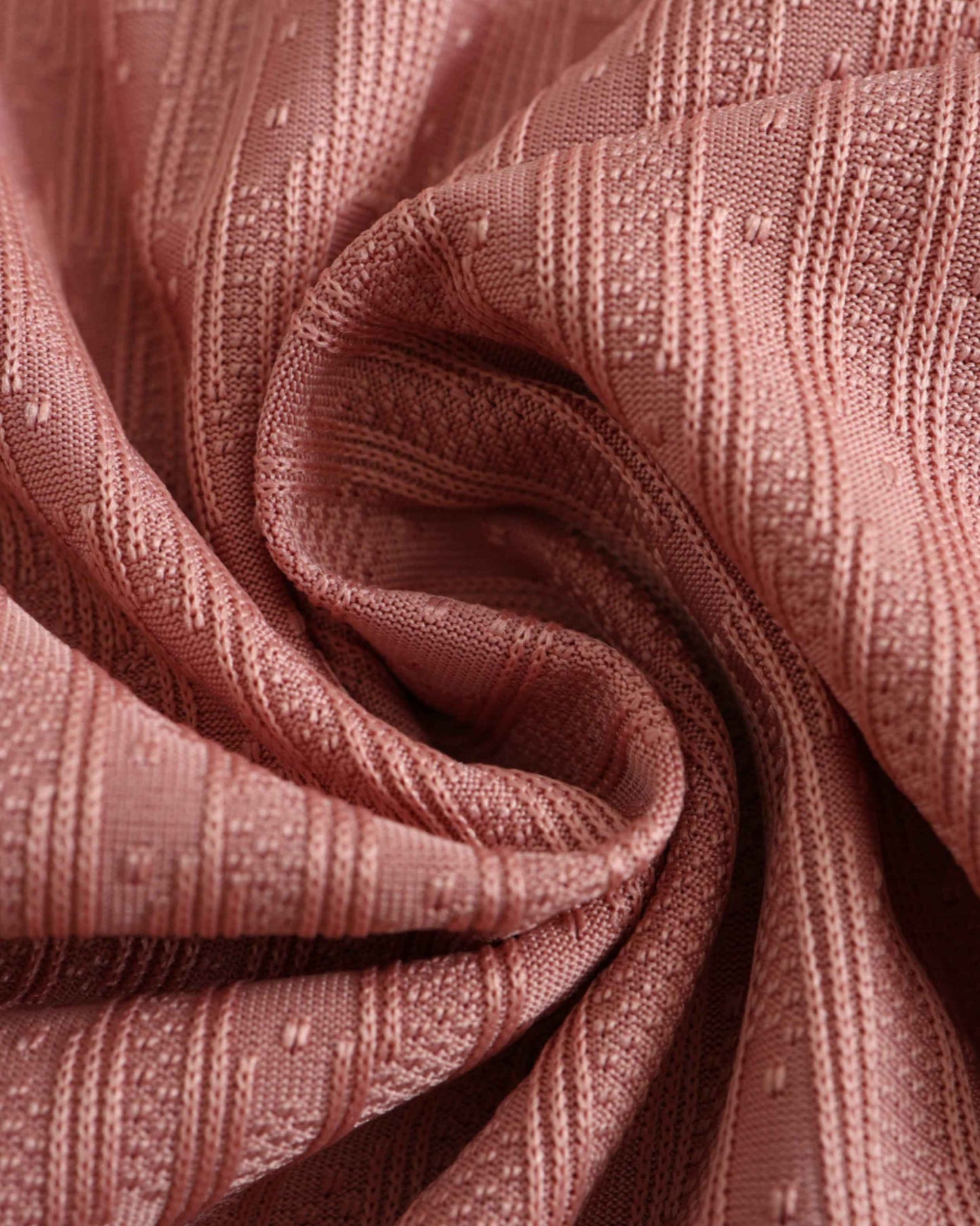A close-up of a pink knitted fabric with a textured pattern.