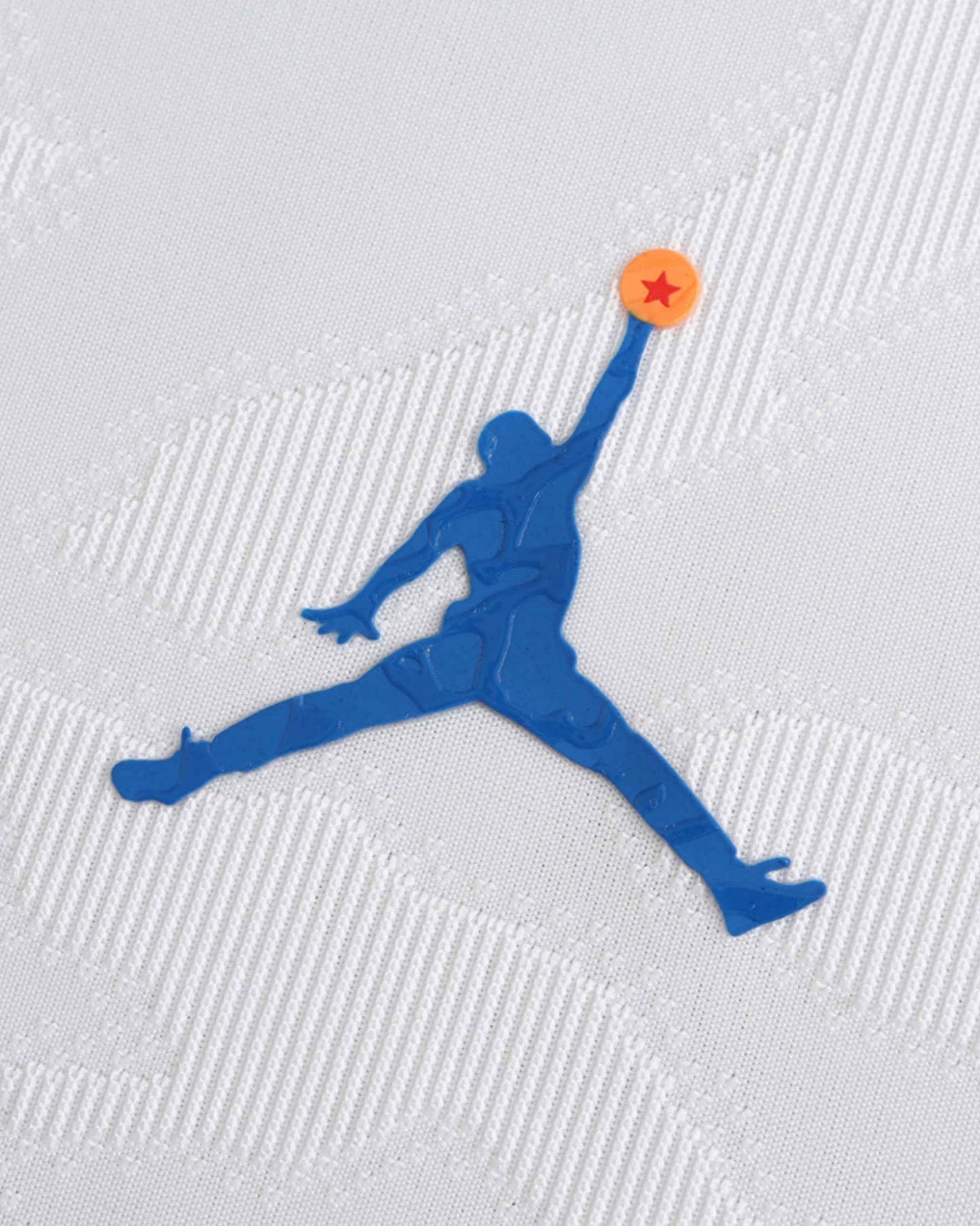 Blue Jumpman logo with an orange star on a white textured soccer jersey.