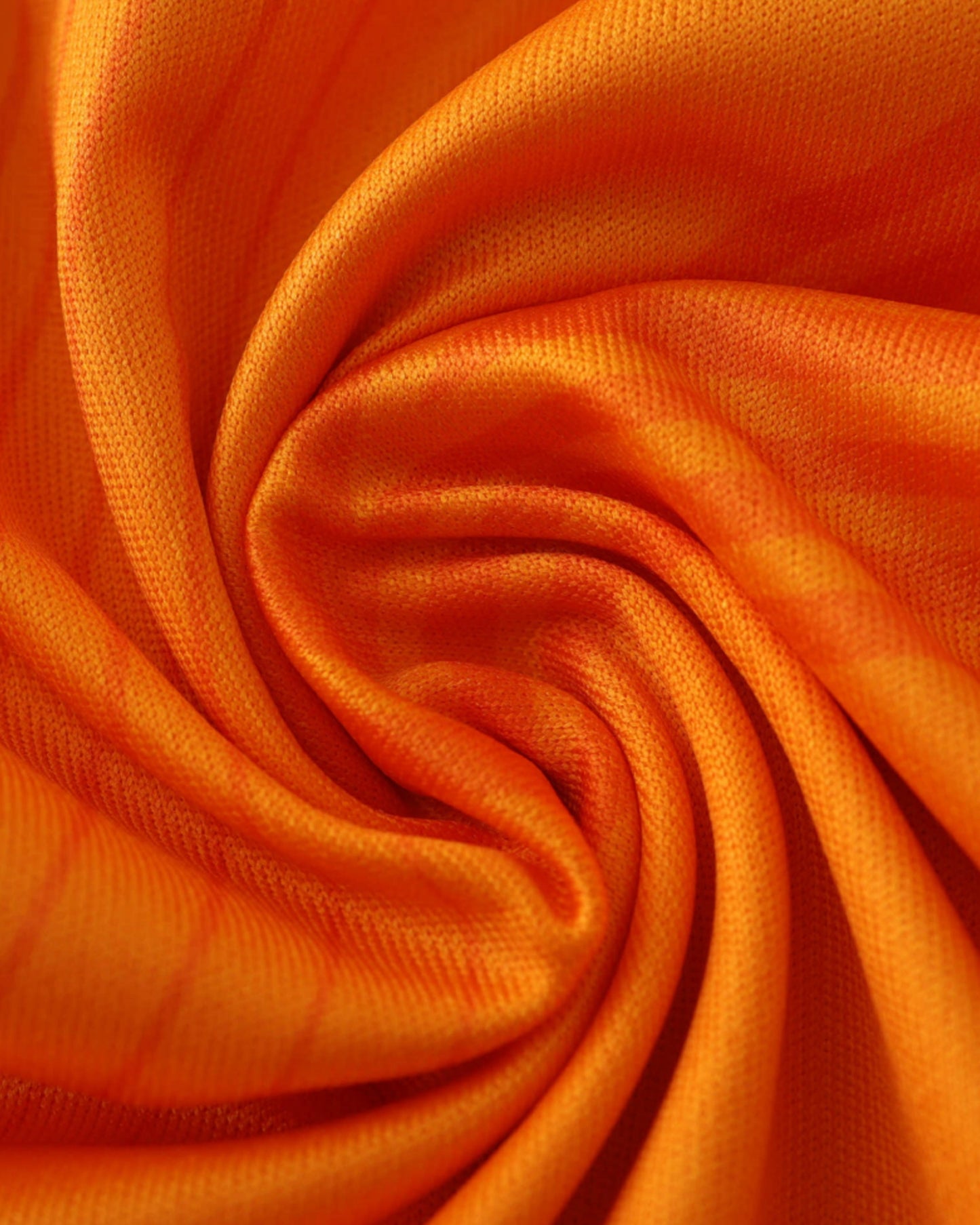 Close-up of orange Real Madrid away football jersey 2024/25 fabric and tonal pattern