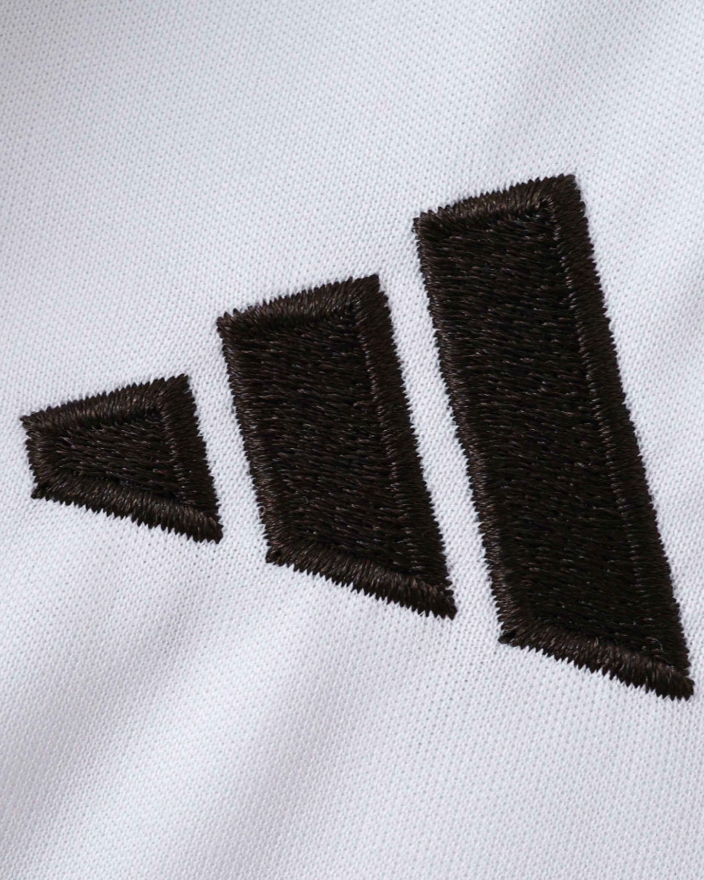 Real Madrid home kids football jersey 2025/26 close-up of embroidered Adidas logo on white fabric