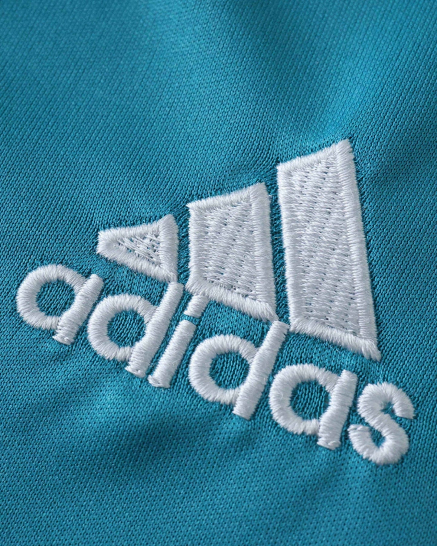 Real Madrid retro third kids football jersey 2017/18 close-up of Adidas logo on teal fabric