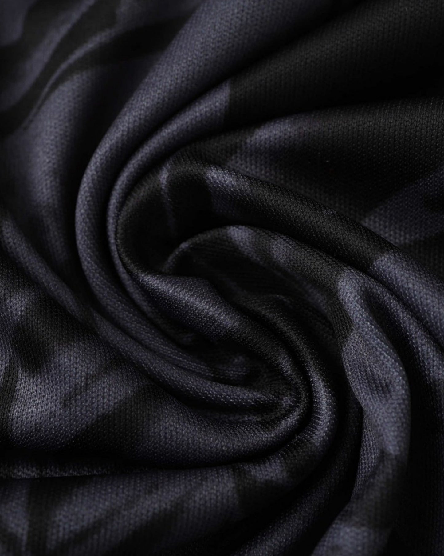 Close-up of the black fabric and grey dragon pattern on the Real Madrid Black Fury football jersey