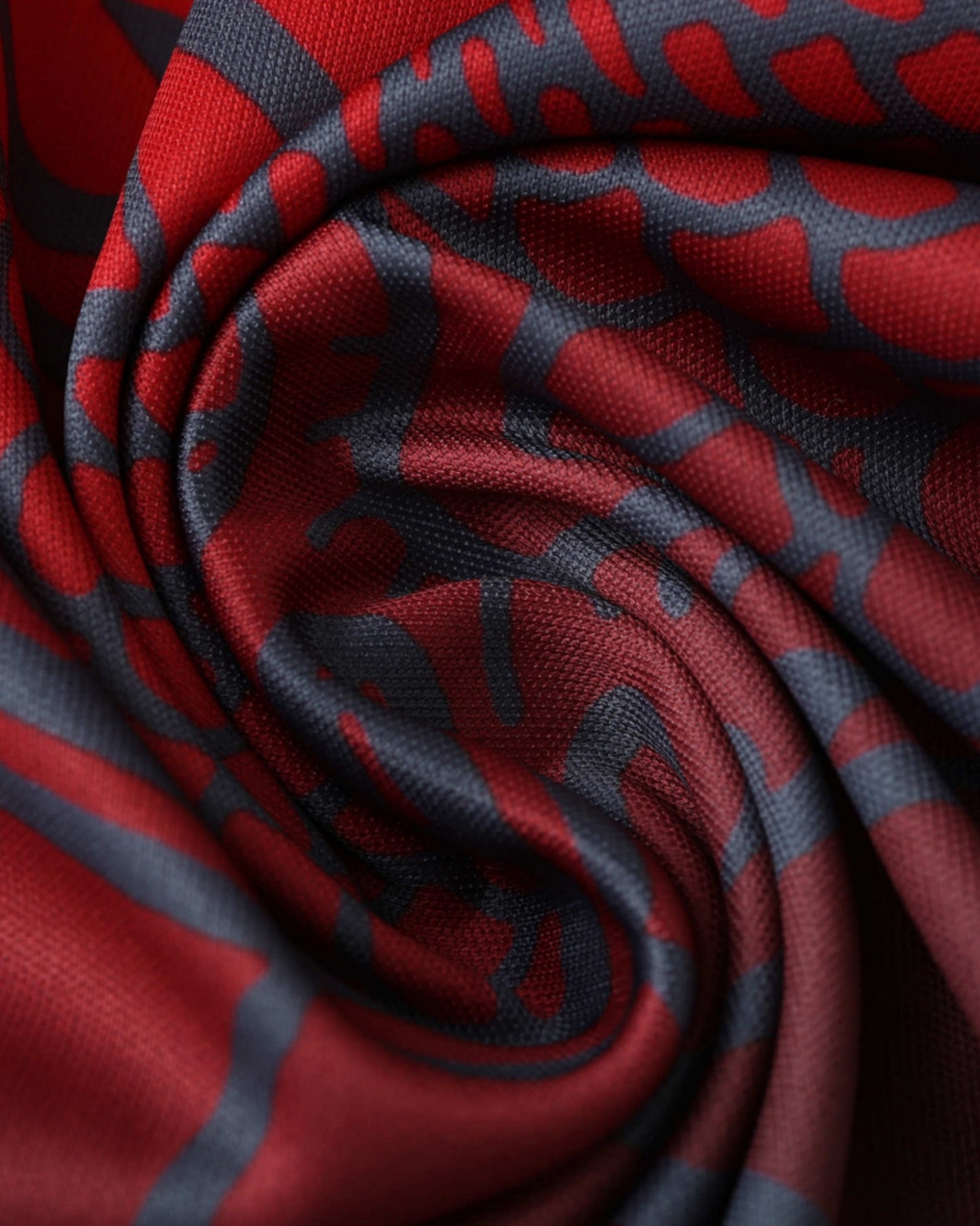 Close-up of red and dark grey dragon-pattern fabric of Crimson Path Real Madrid jersey