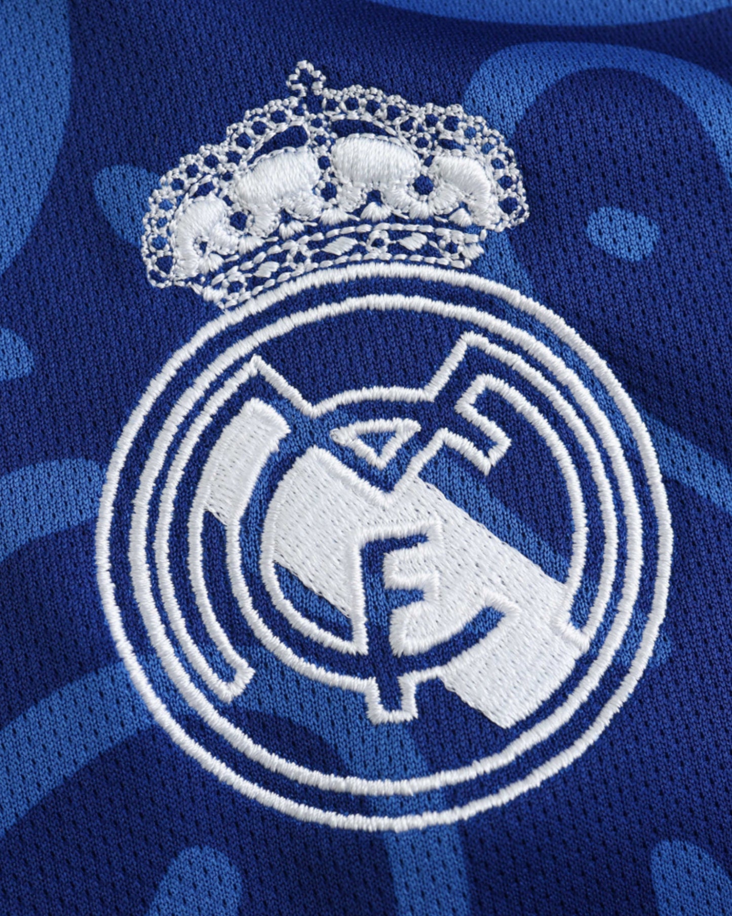Close-up of embroidered Real Madrid crest and crown on blue El Palacio football jersey