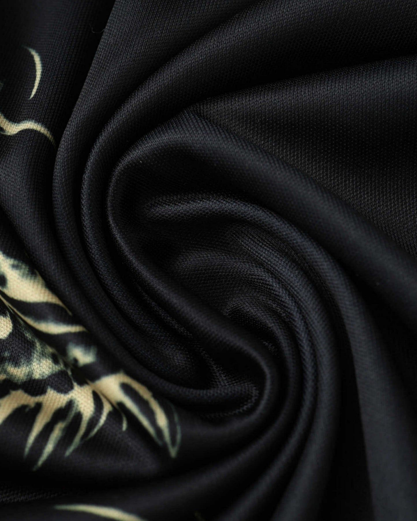Close-up of black fabric with gold dragon print of Real Madrid Light Falkor jersey