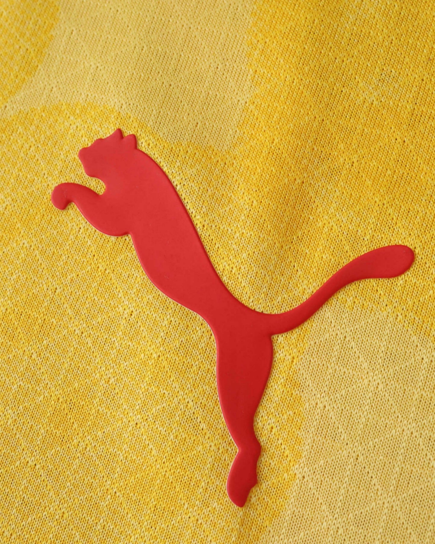 A red Puma logo is on a yellow textured fabric.