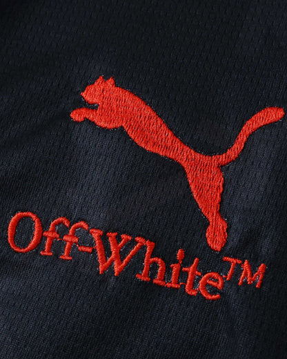 AC Milan x Off-White football jersey detail showing red Puma and Off-White logos on black fabric