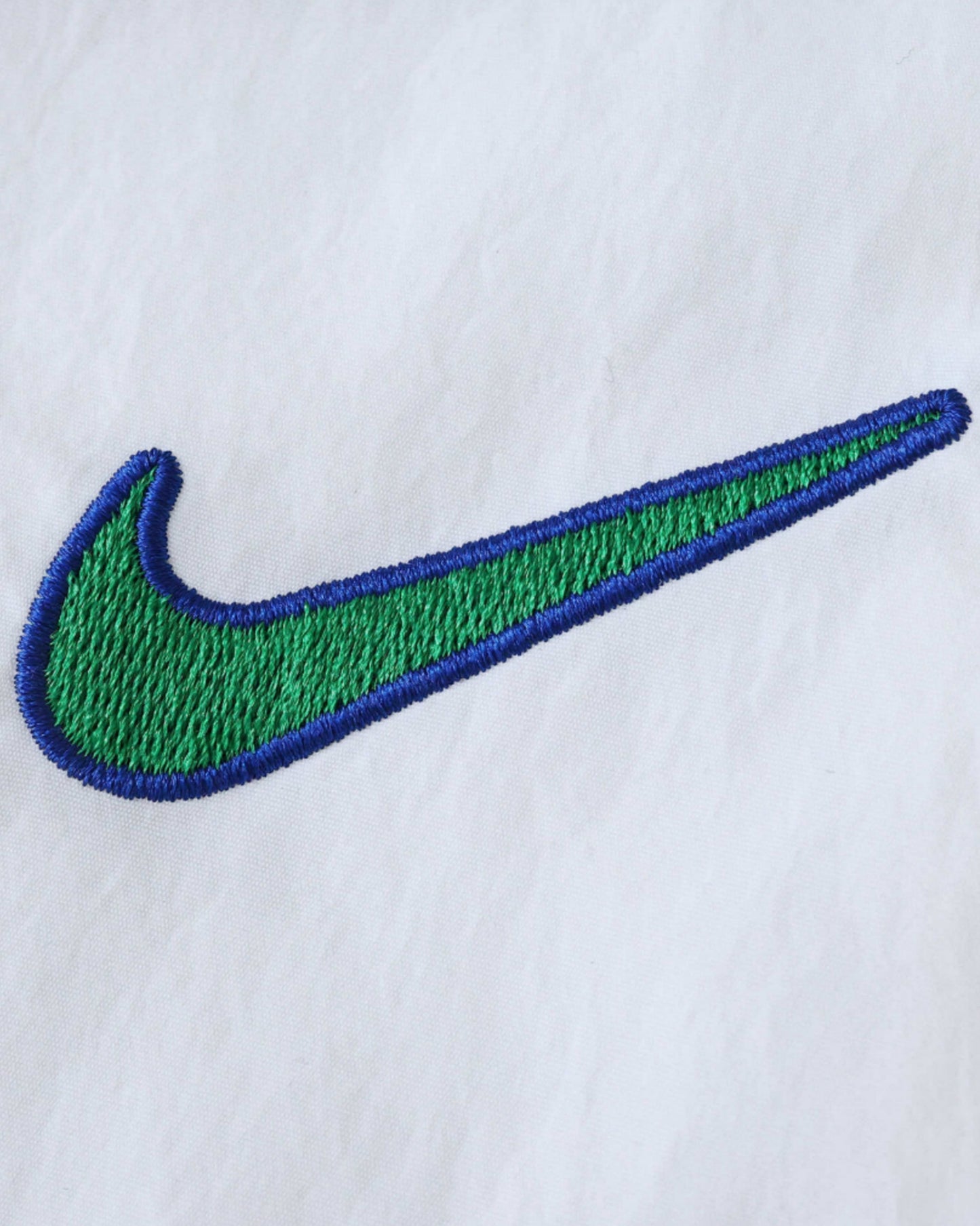 Embroidered green and blue Nike logo on a white background.