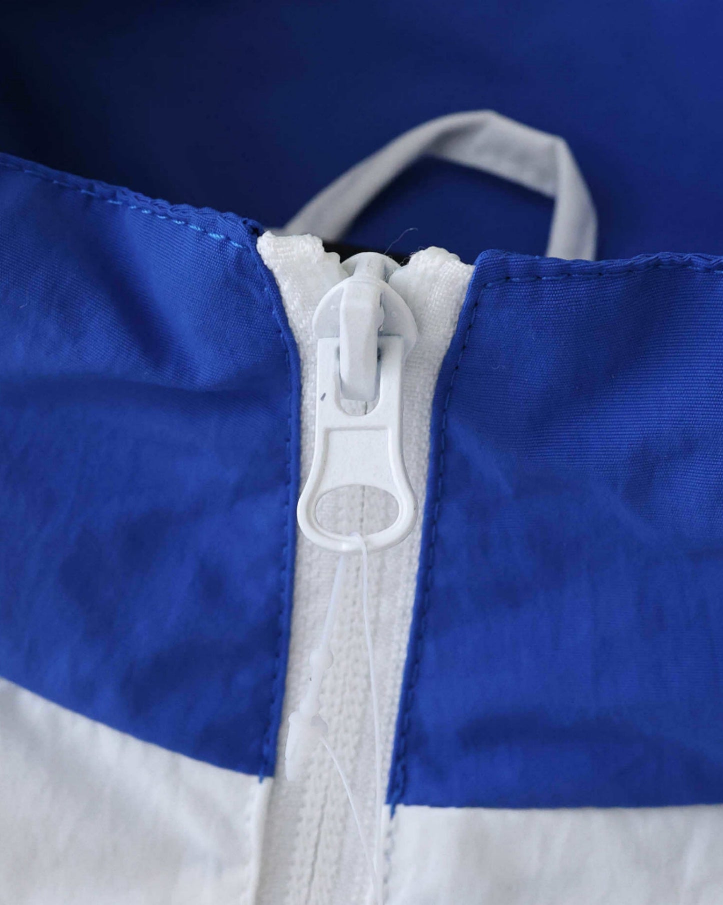 Close-up of a white zipper on a blue and white Brazil soccer windbreaker jacket.