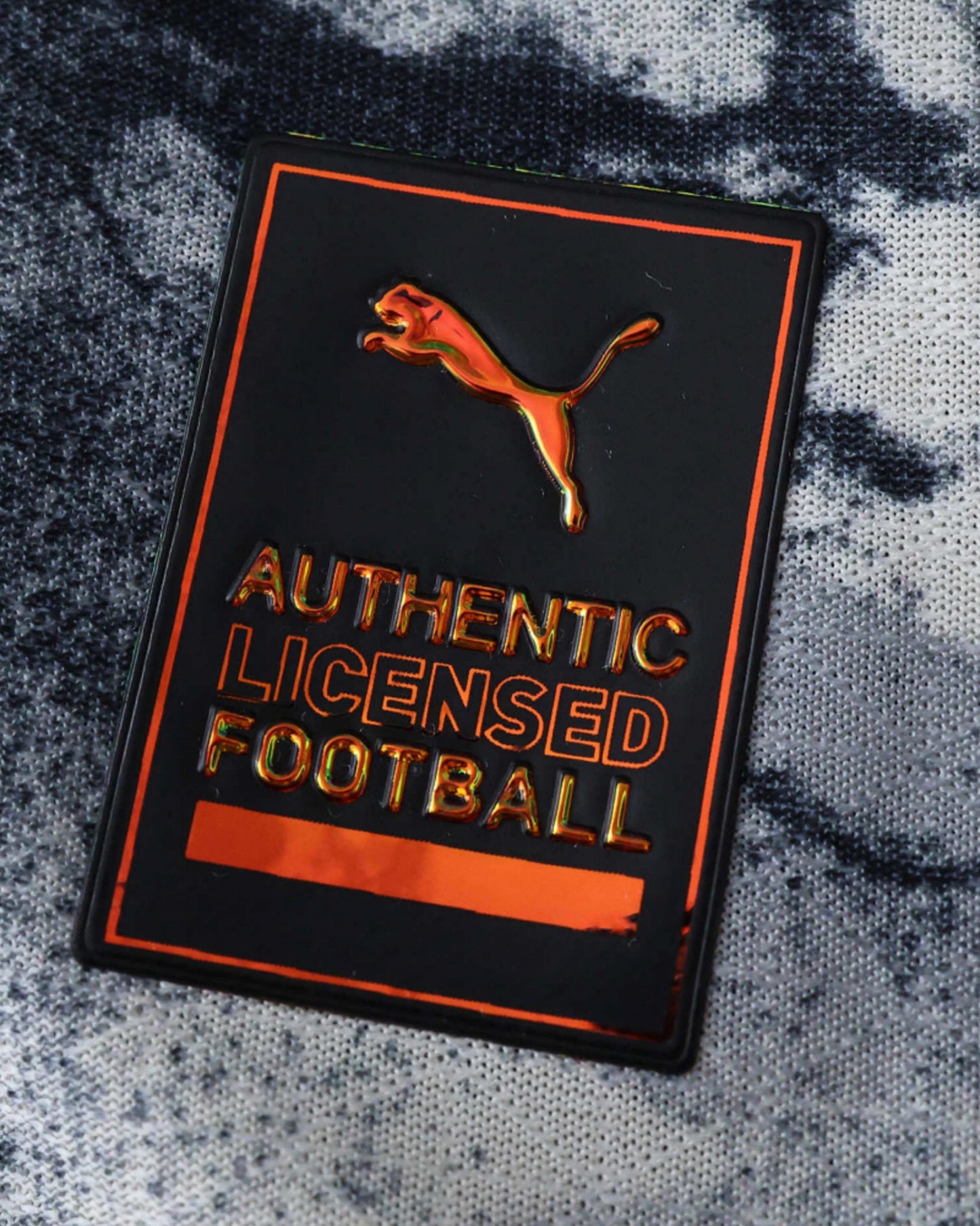 A black tag with an orange Puma logo and text that reads "AUTHENTIC LICENSED FOOTBALL".
