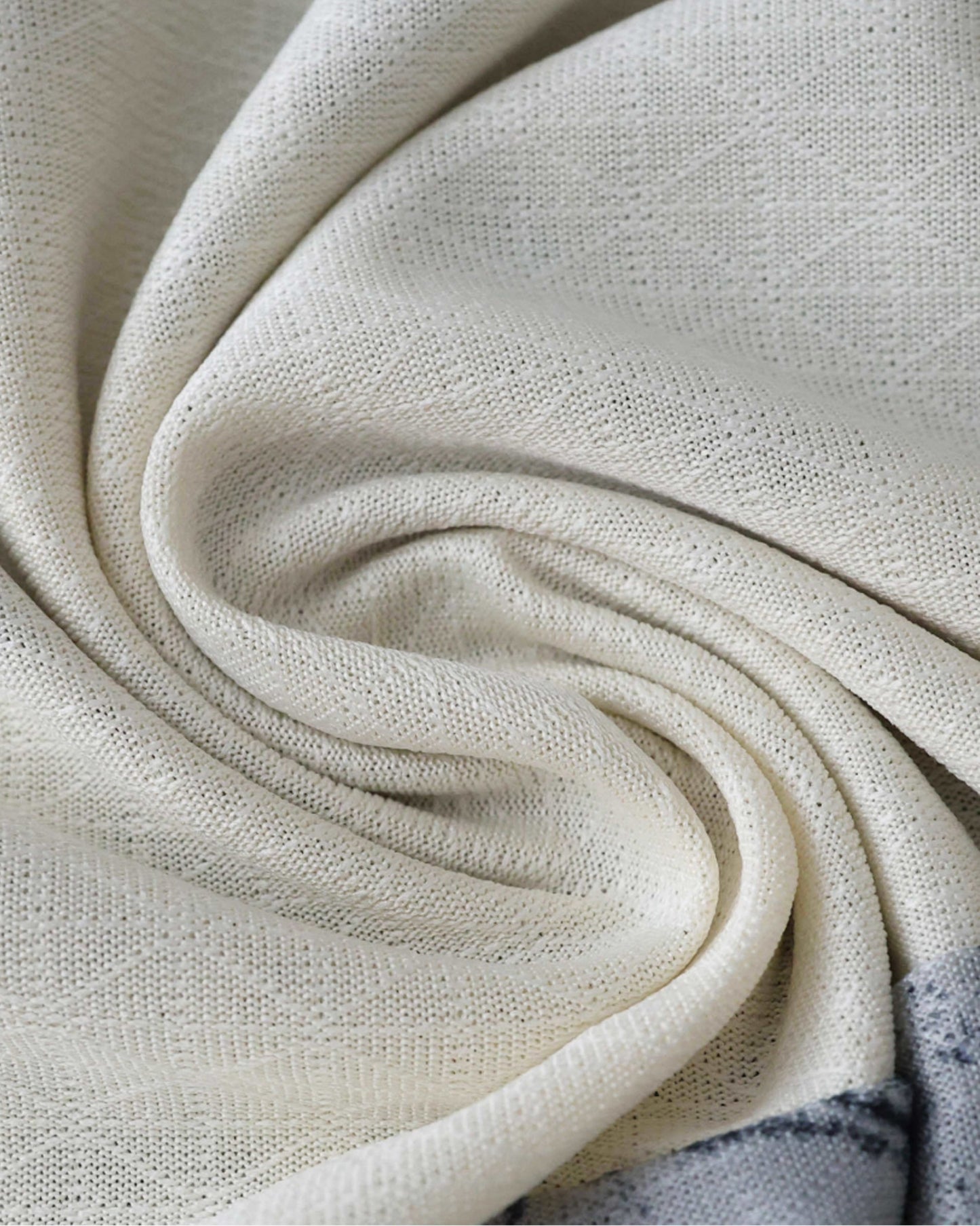 A close-up of a white knitted fabric with a subtle pattern and a grey border.