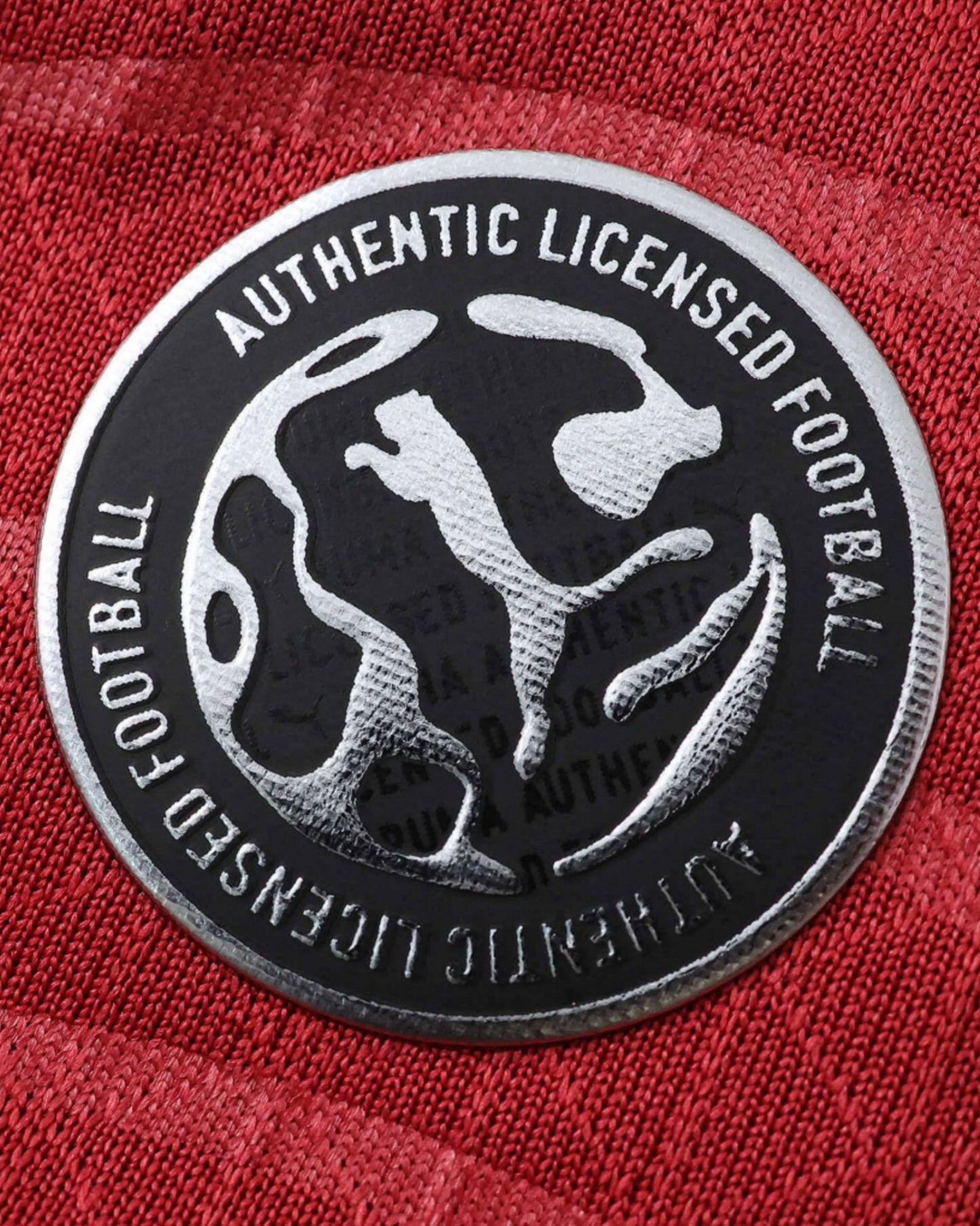 A close-up of a red football jersey with an authentic licensed football badge.