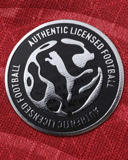 A close-up of a red football jersey with an authentic licensed football badge.
