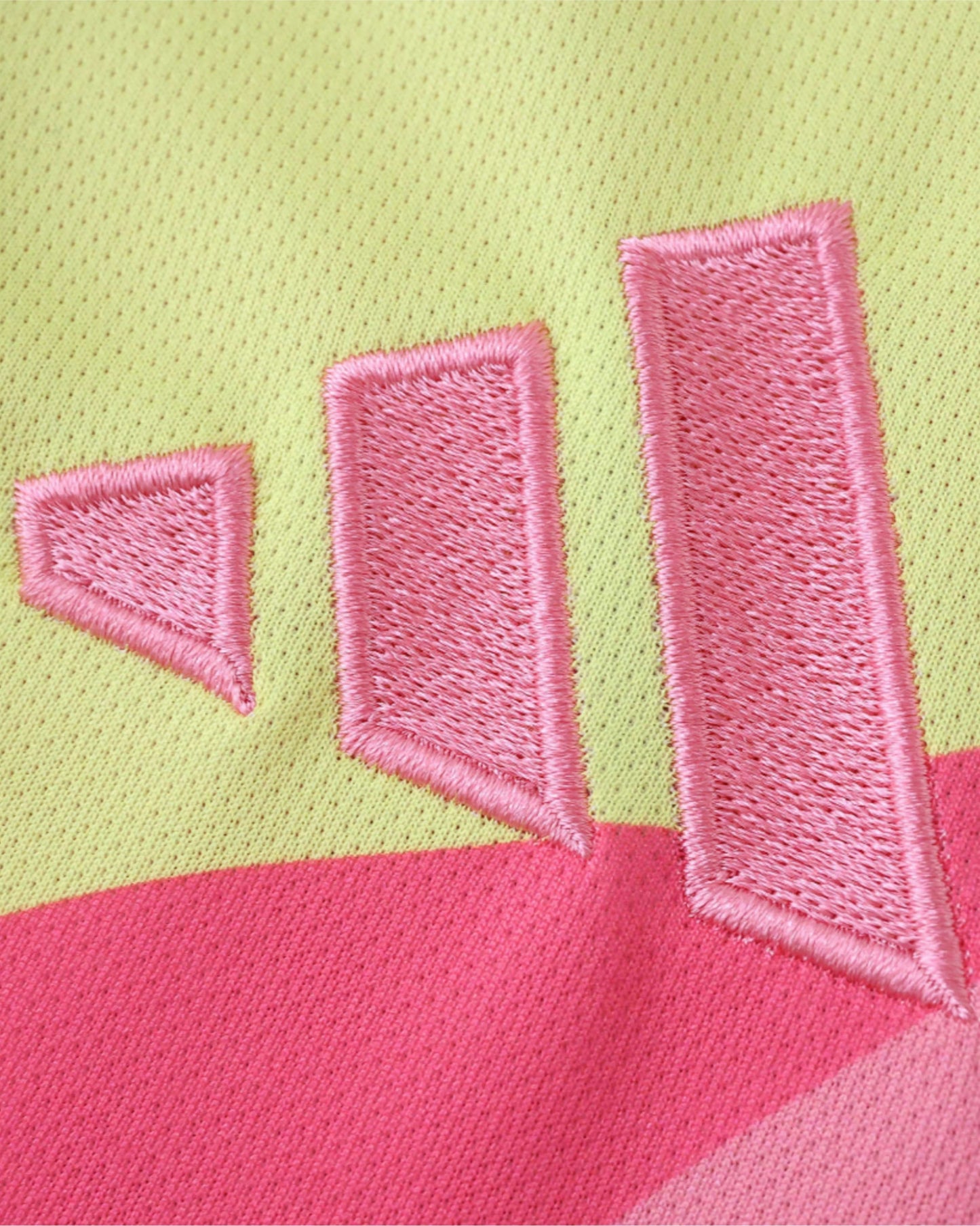 A yellow and pink football shirt with embroidered pink stripes.